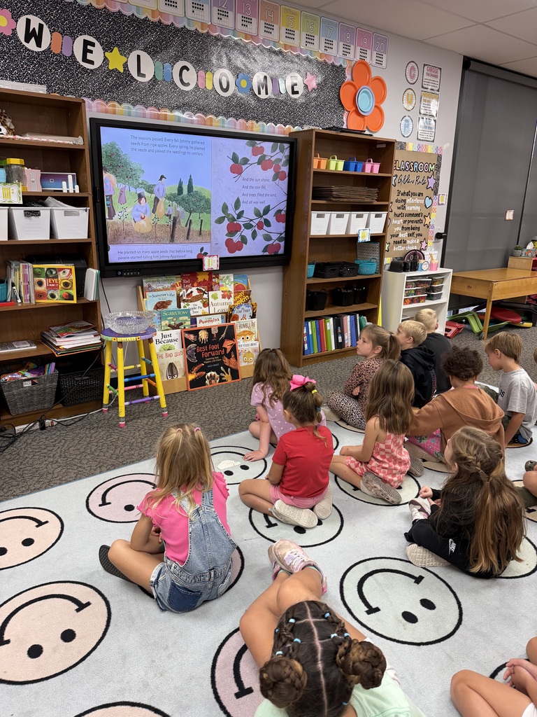 Students sitting on the floor watching an apple video.