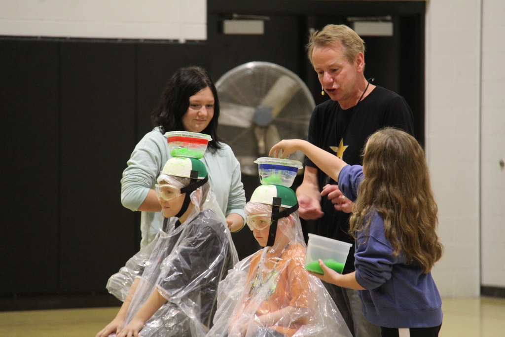 Students adding Slime to the bowls attached to the top of the other students hats. 