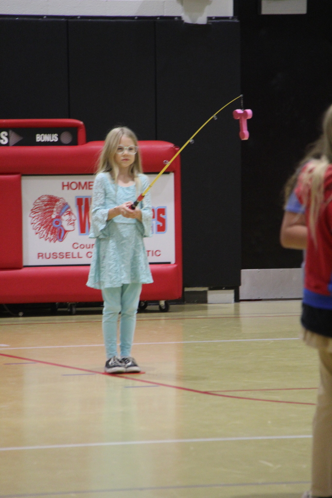 A student holding the fishing pole with a T. The first letter in TRUST.