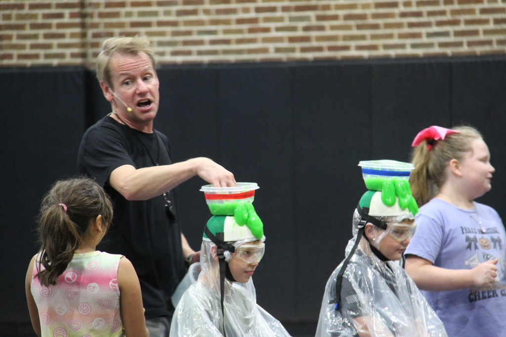 Speaker squishing the slime in the bowl on top of the students head. 