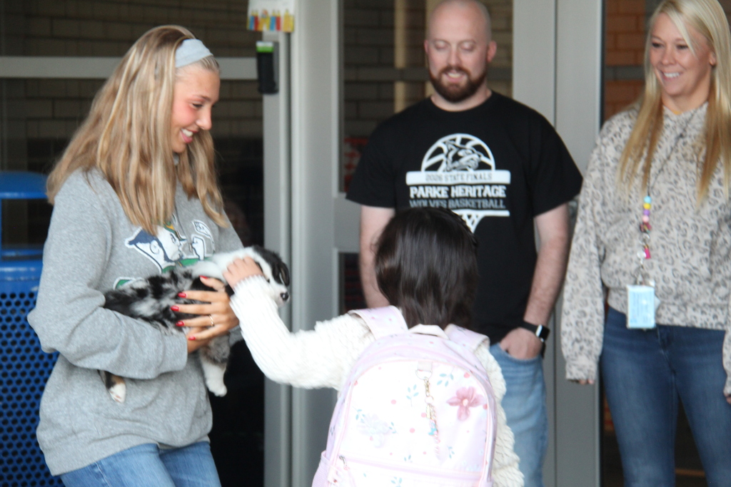 One of the athletes holds a puppy as a student pets it as she walks into school this morning. 