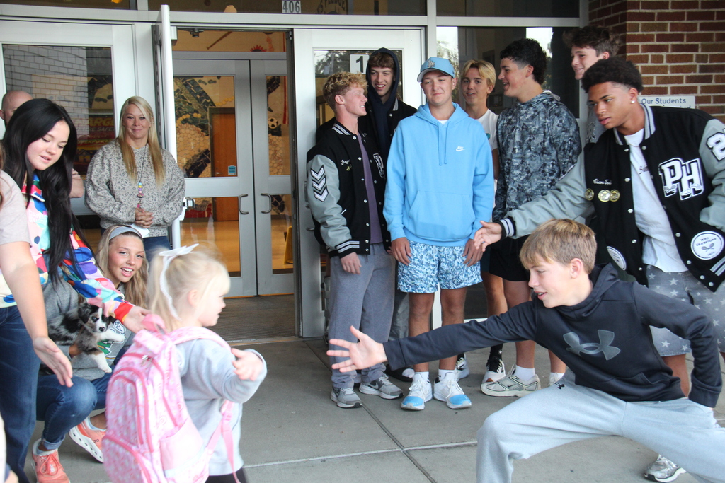 One of the students and an athlete reach their hands out to high five as the student walks into school this morning. 