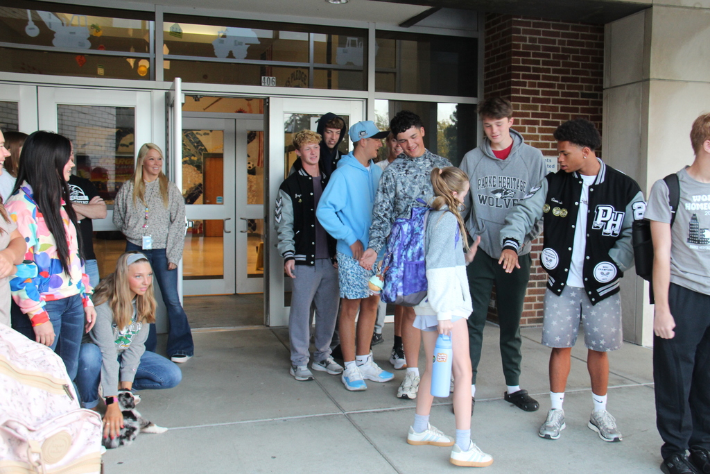 One of the students high fives some of the boy athletes as she walks into school. 