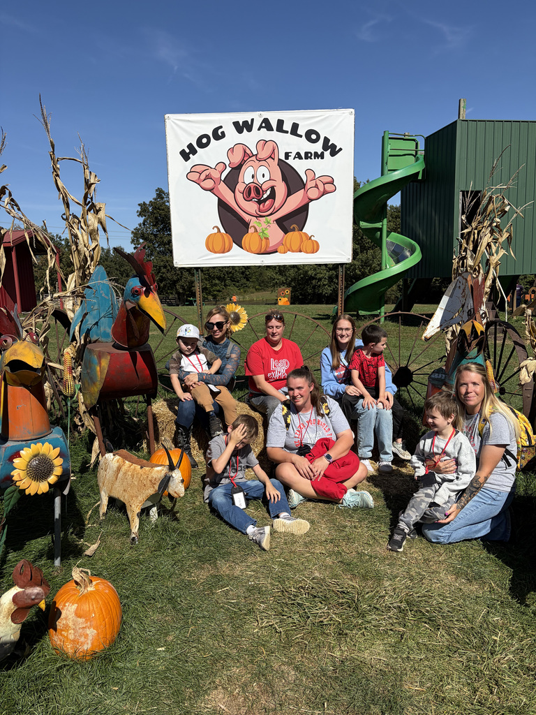 Students and parents pose for a photo in front of the hog wallow farm photo op. 