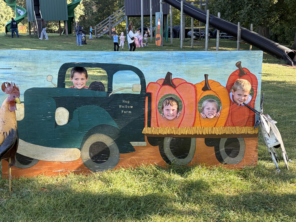 4 students pose in the photo cut out of a truck with pumpkins in the back. 