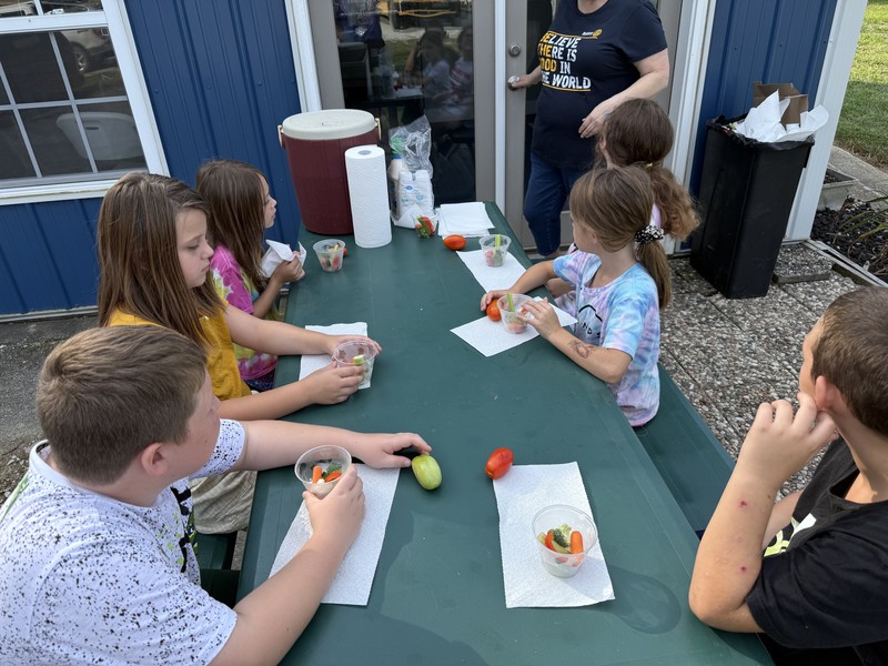 students sitting at a table eating vegetables