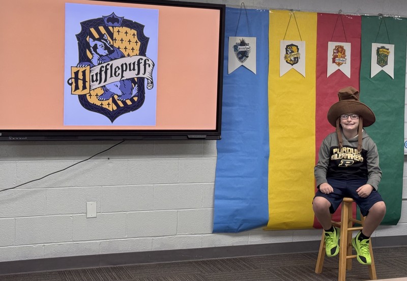 student sitting on a stool wearing the Harry Potter sorting hat