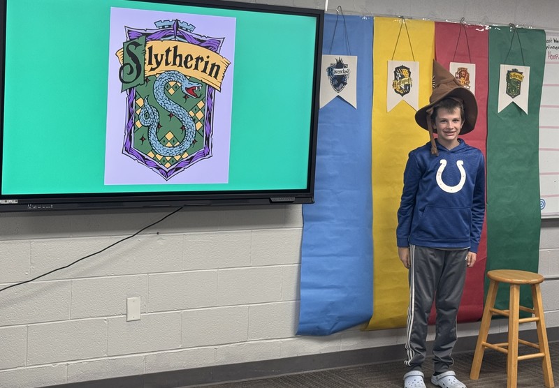 student sitting on a stool wearing the Harry Potter sorting hat
