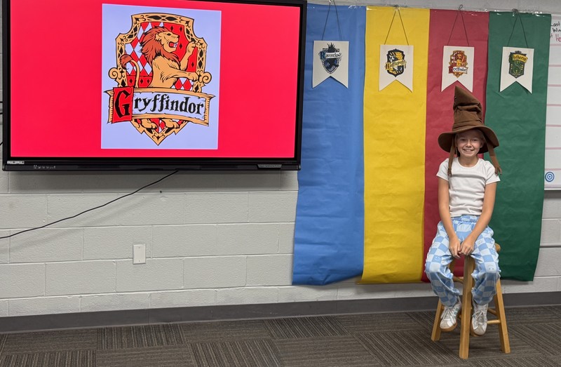 student sitting on a stool wearing the Harry Potter sorting hat