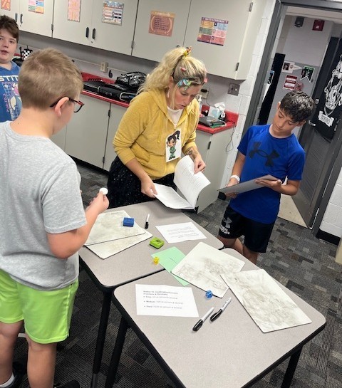 two students and the math teacher working on their papers