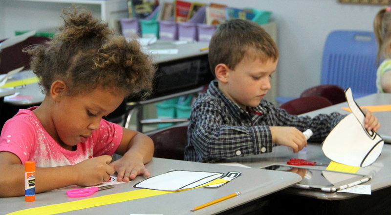two students working on a Johnny Appleseed hat