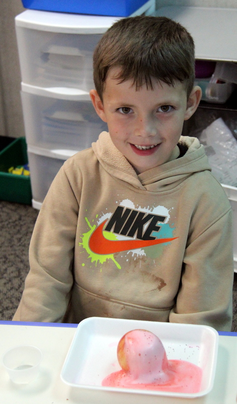 a boy with an apple completing a science experiment