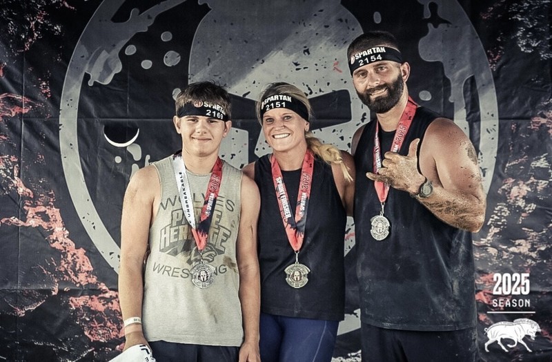 a teenage boy, a woman and a man standing together wearing medals
