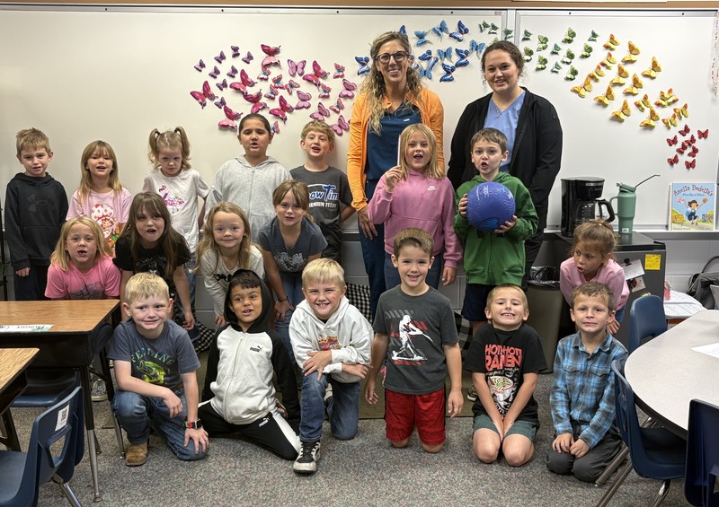 students sitting, kneeling and standing in rows with two adults