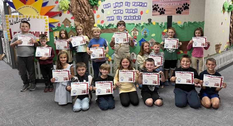 students sitting, kneeling and standing and holding certificates