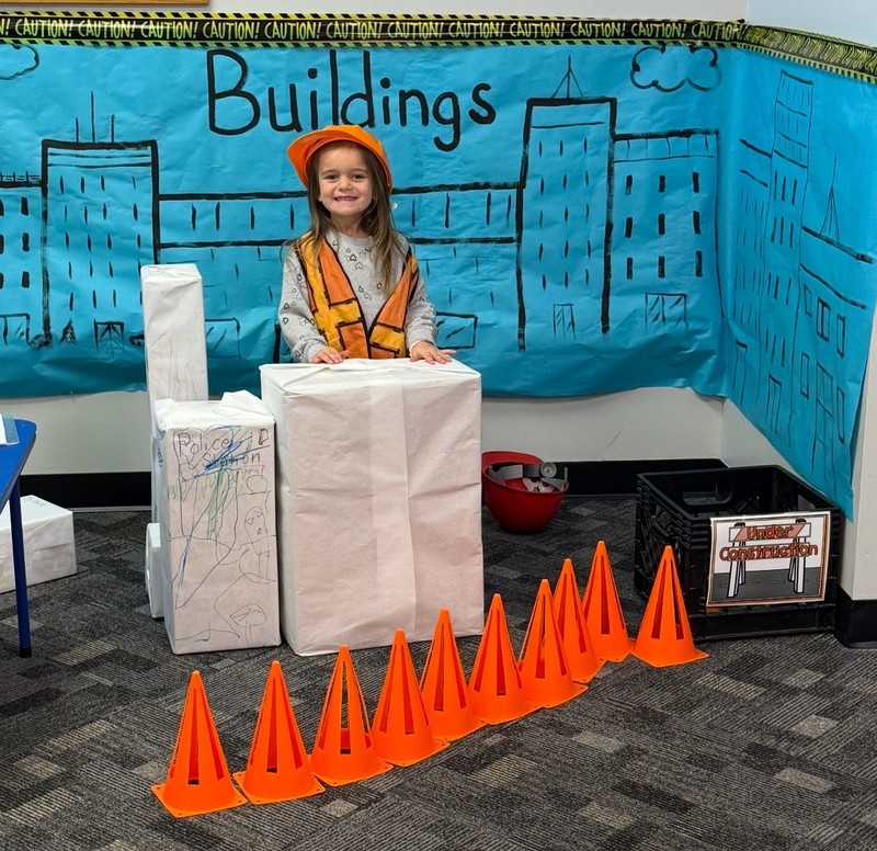 preschool student standing behind a box building