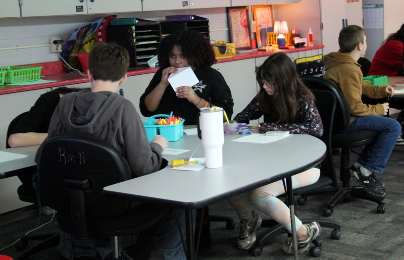 students sitting at tables making cards