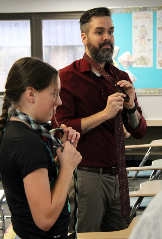 teacher showing a student how to tie a tie