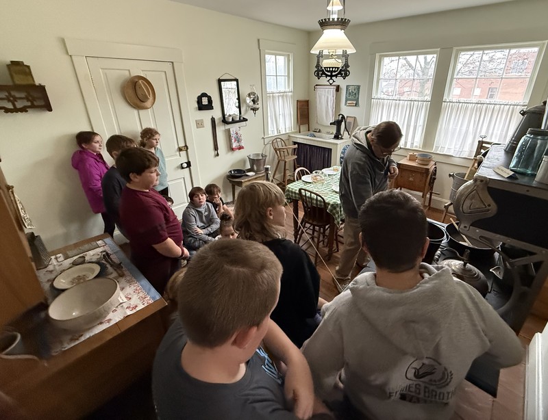 students listening to the tour guide in the kitchen of the Ernie Pyle house