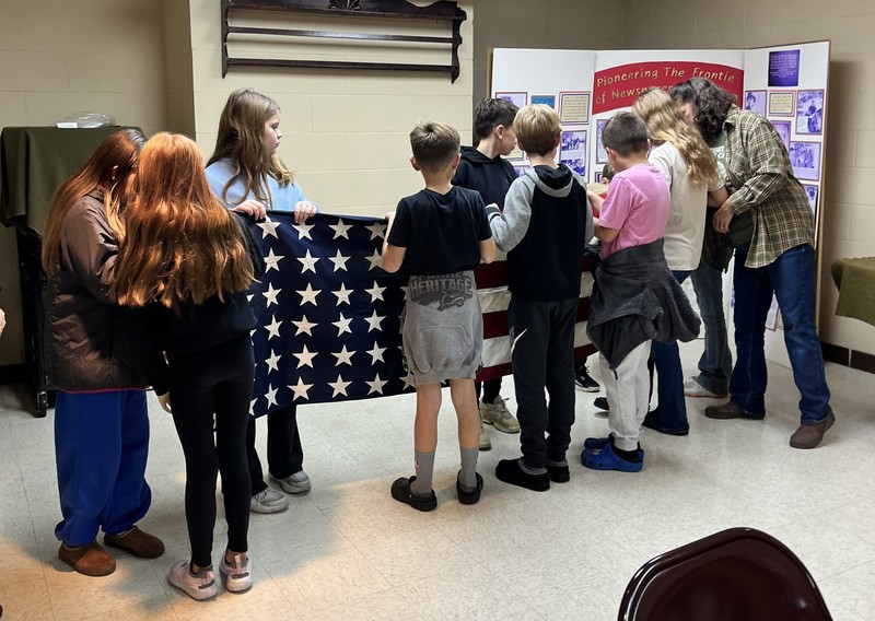 students learning to fold a flag