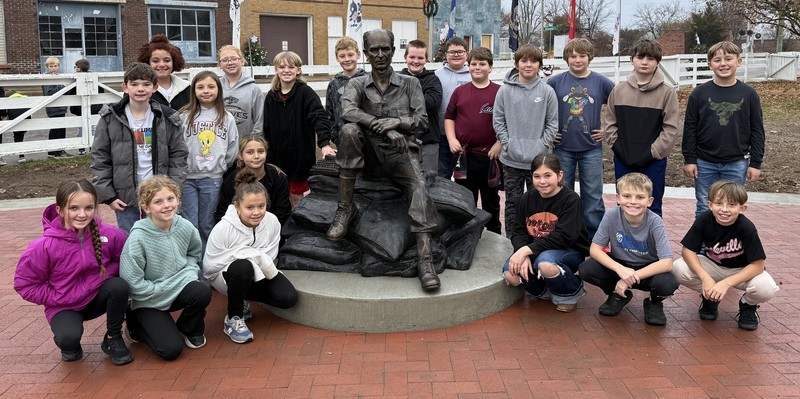 students sitting and standing by the Ernie Pyle staute
