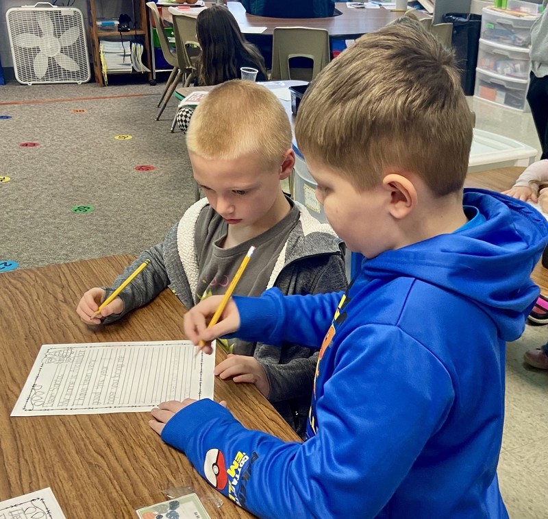 two boys sitting at a desk and writing a letter to Santa