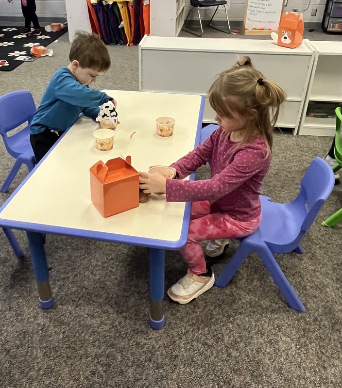 preschool students sitting at a table with plush puppies