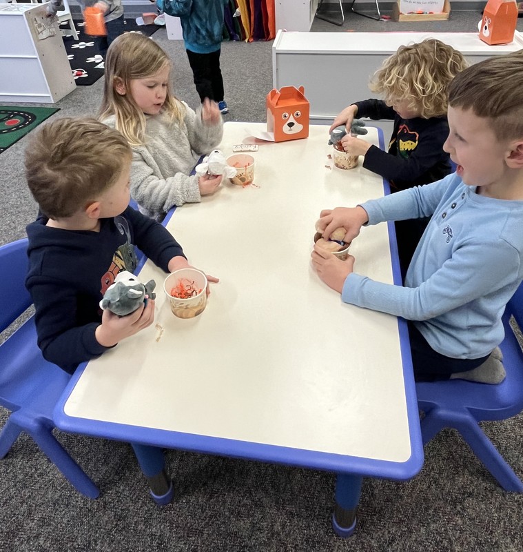 preschool students sitting at a table with plush puppies