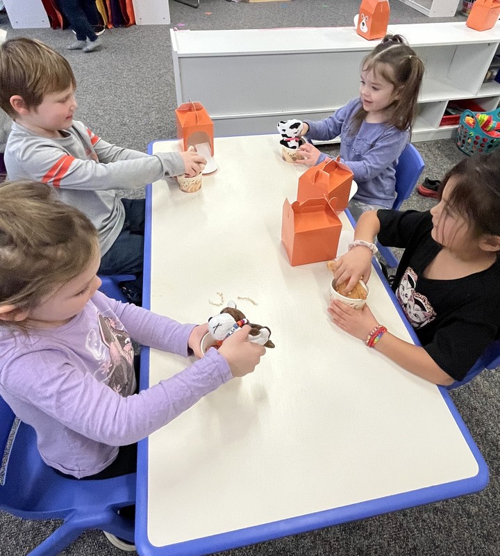 preschool students sitting at a table with plush puppies