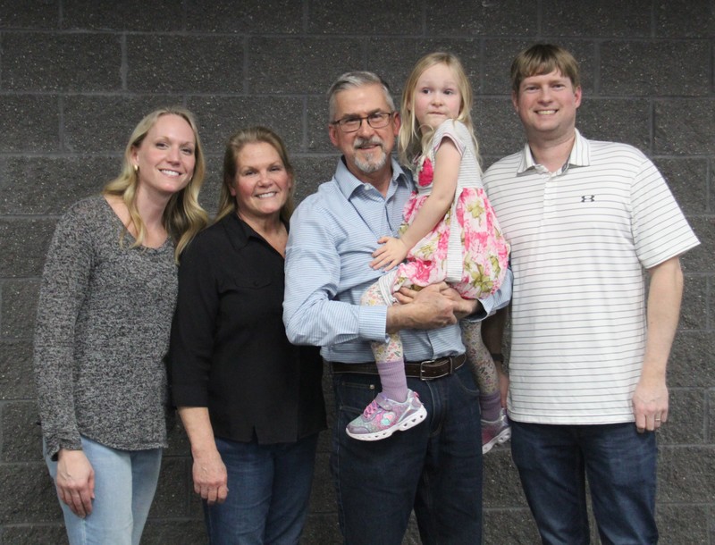 four people standing in a row with one person holding a girl