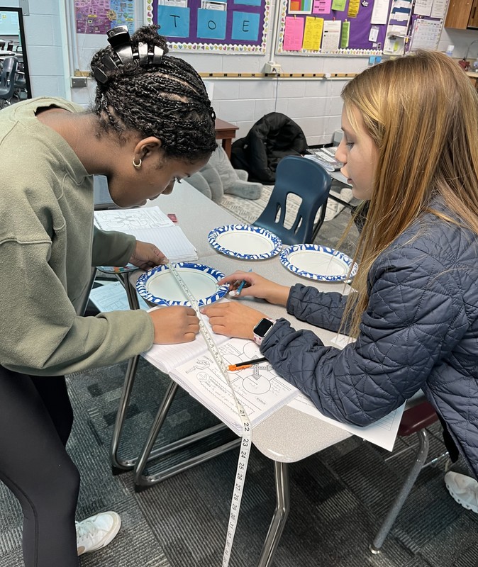 two students measuring a circled plate