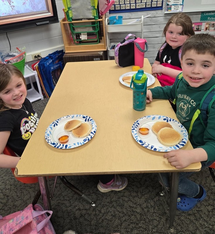 students sitting at a table with plates of pancakes
