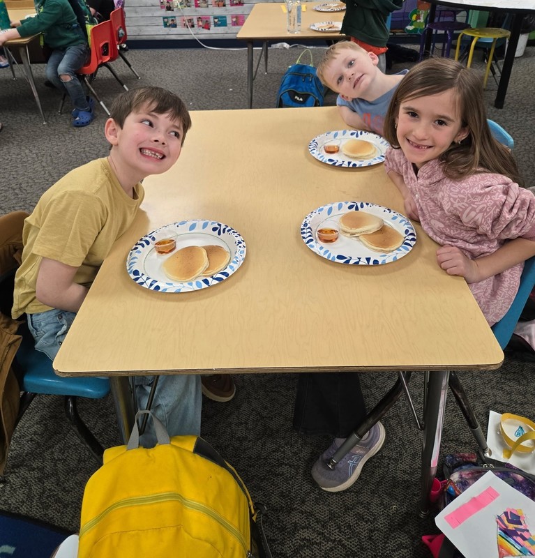 students sitting at a table with plates of pancakes