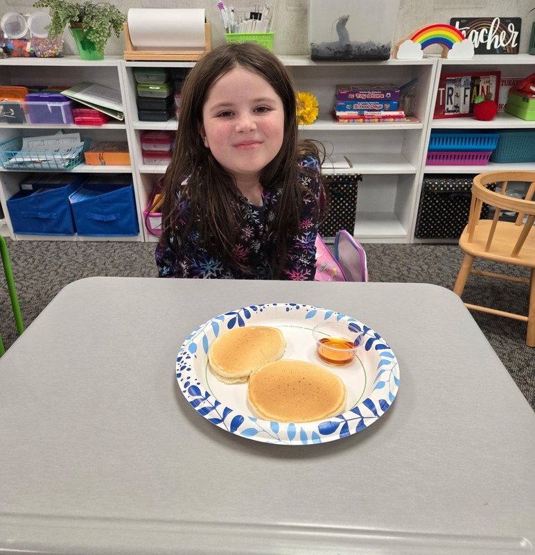 student sitting at a table with a plate of pancakes