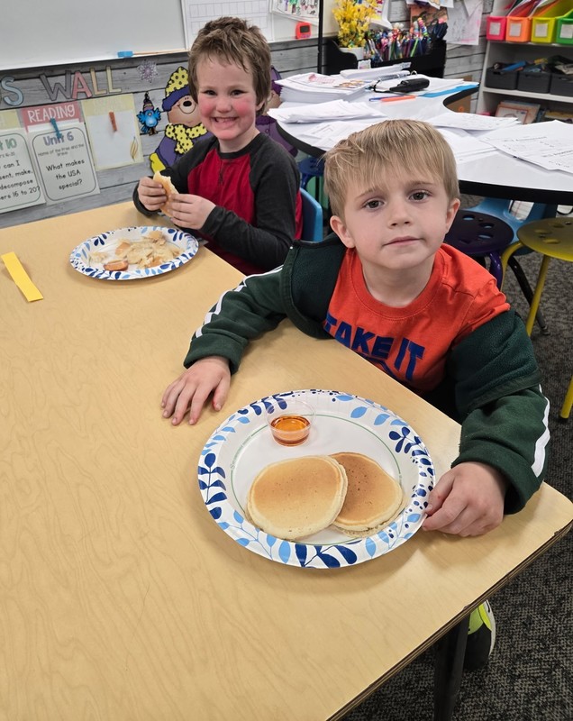 students sitting at a table with plates of pancakes
