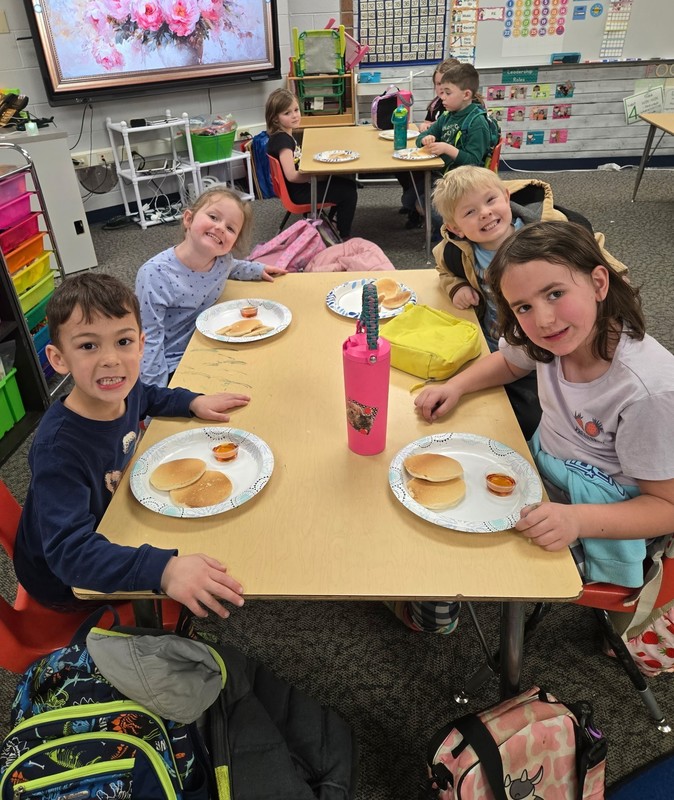 students sitting at a table with plates of pancakes