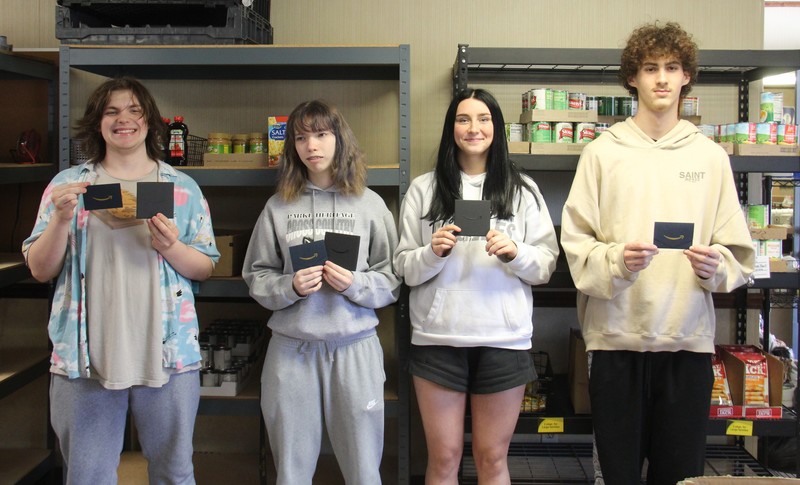 four students standing in a row holding gift cards