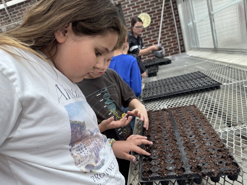 students planting seeds in a greenhouse