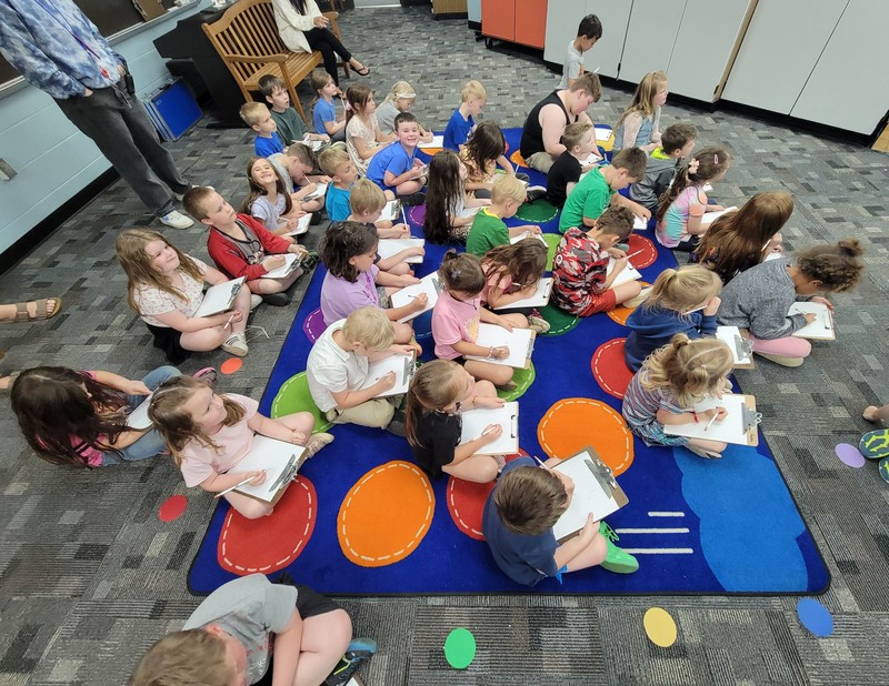 students sitting on the floor with clipboards