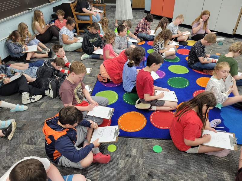 students sitting on the floor with clipboards