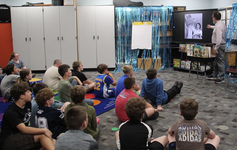 photo of students sitting on the floor listening to a guest author speak