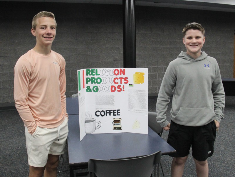 two boys standing with their diplay board on Italy between them