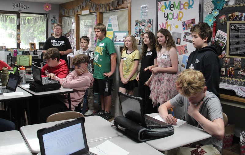 students standing and sitting at desks