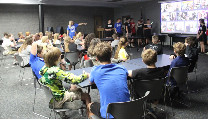 students sitting at tables listening to speakers