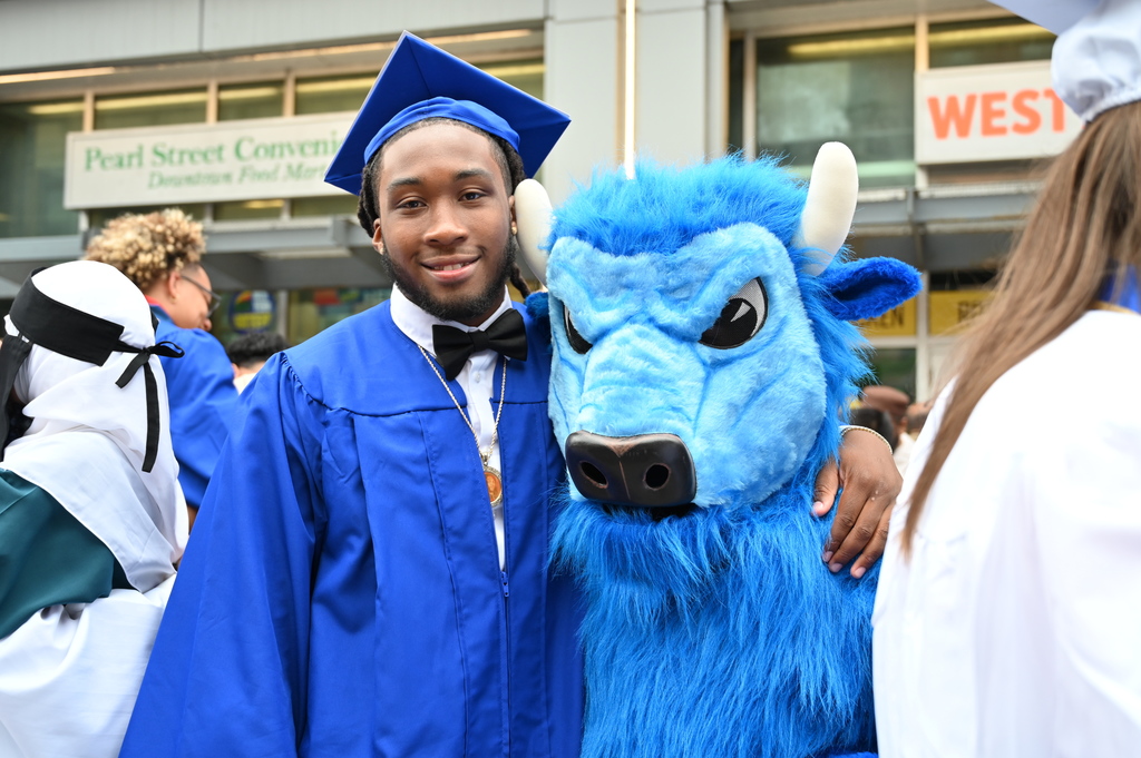 A Shaker graduate poses with his arm around the Bison mascot.