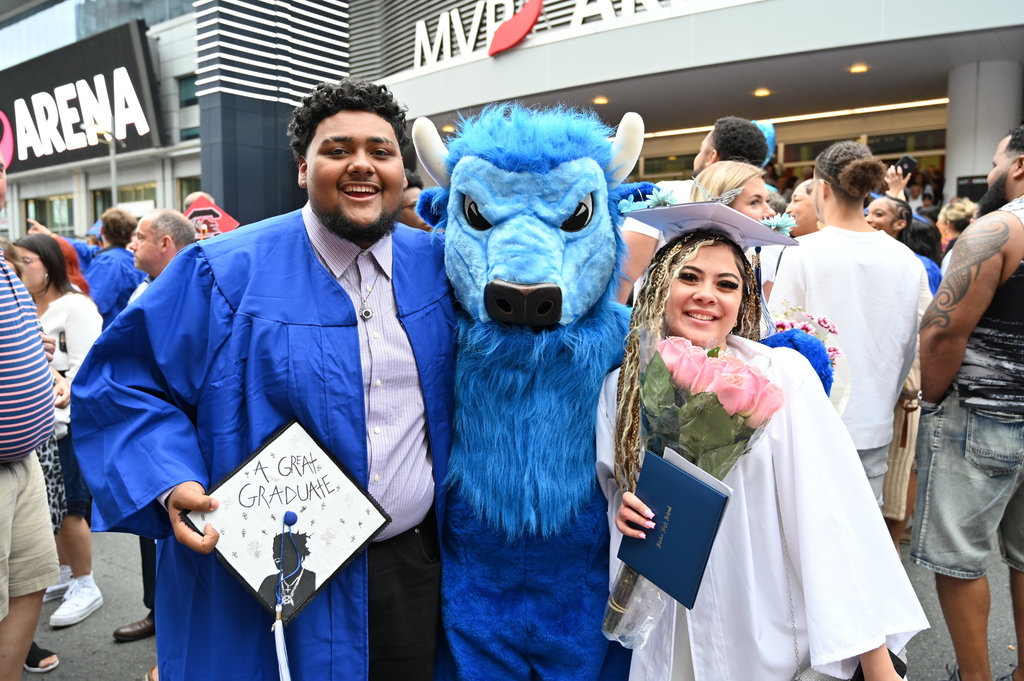 Two graduates pose with the Bison mascot.