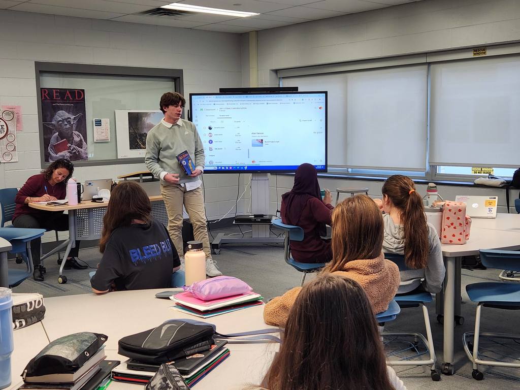 Students presenting to middle school students in the library