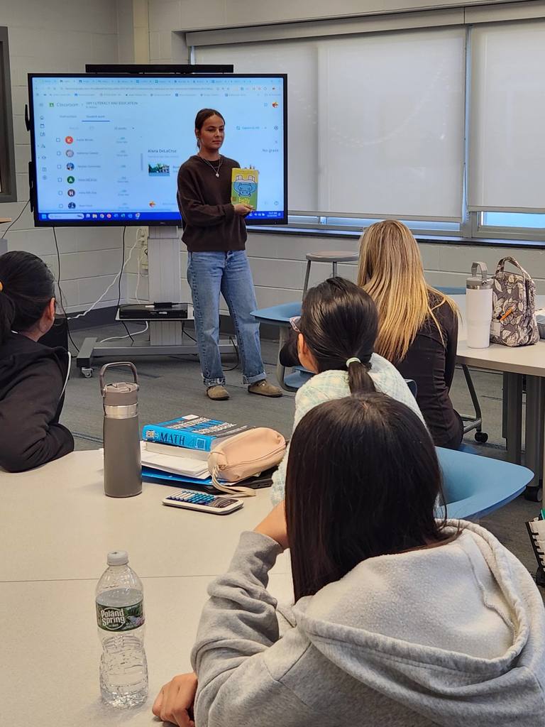 Students presenting to middle school students in the library