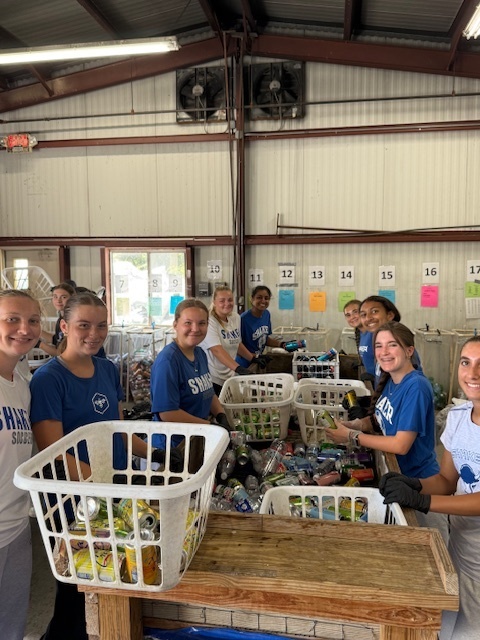 Girls soccer team members helping sort bottles and cans