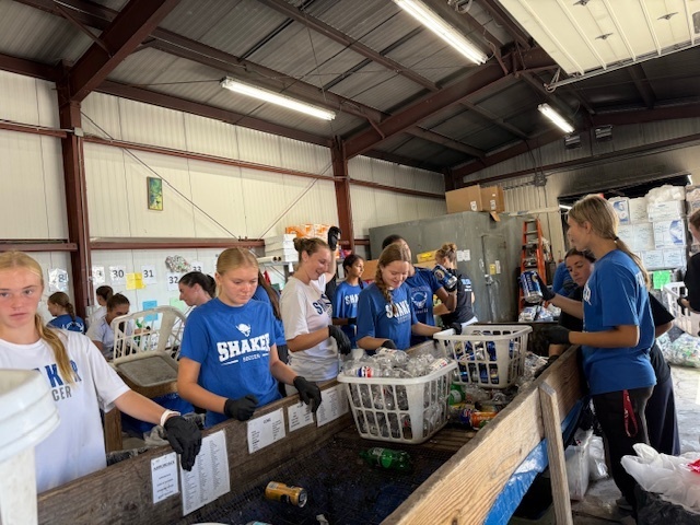 Girls soccer team members helping sort bottles and cans